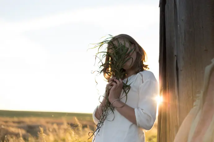 Jeune fille tenant un bouquet de verdure devant son visage